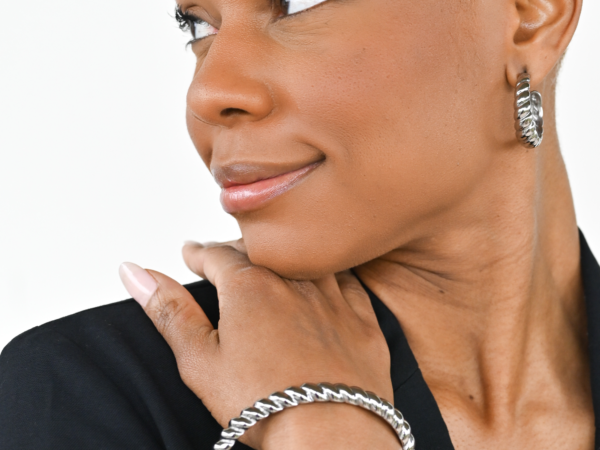 Woman wearing twisted silver hoop earrings and bracelet