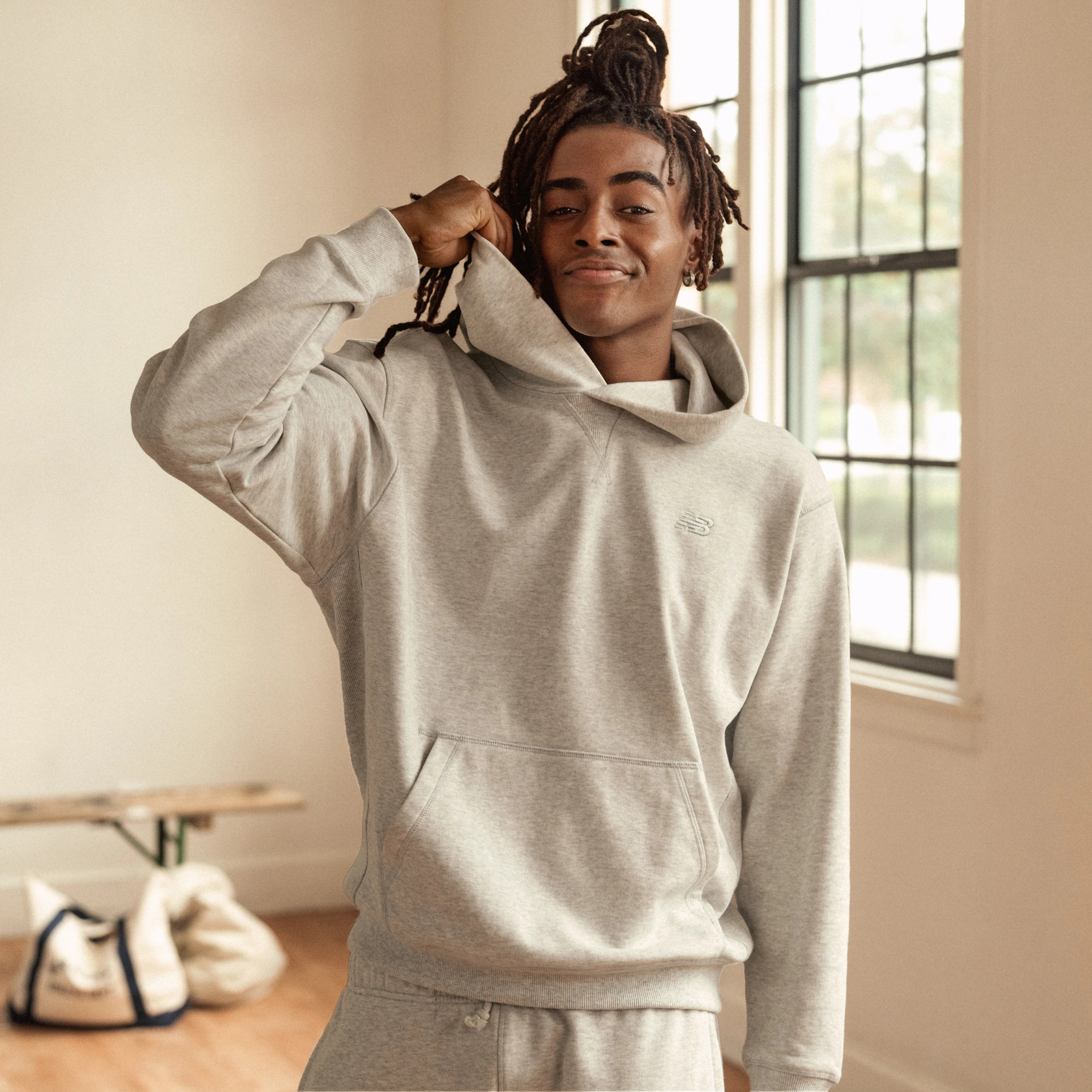 Smiling man in gray hoodie indoors by window