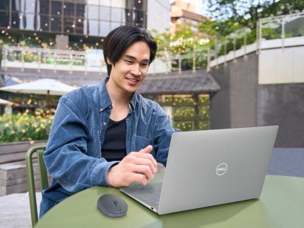 Young man working on laptop outdoors at green table