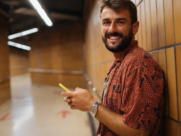Smiling man using phone in underground corridor