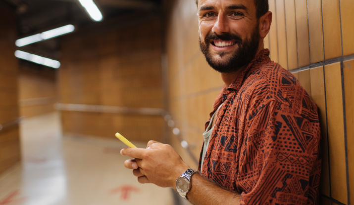Smiling man using phone in underground corridor