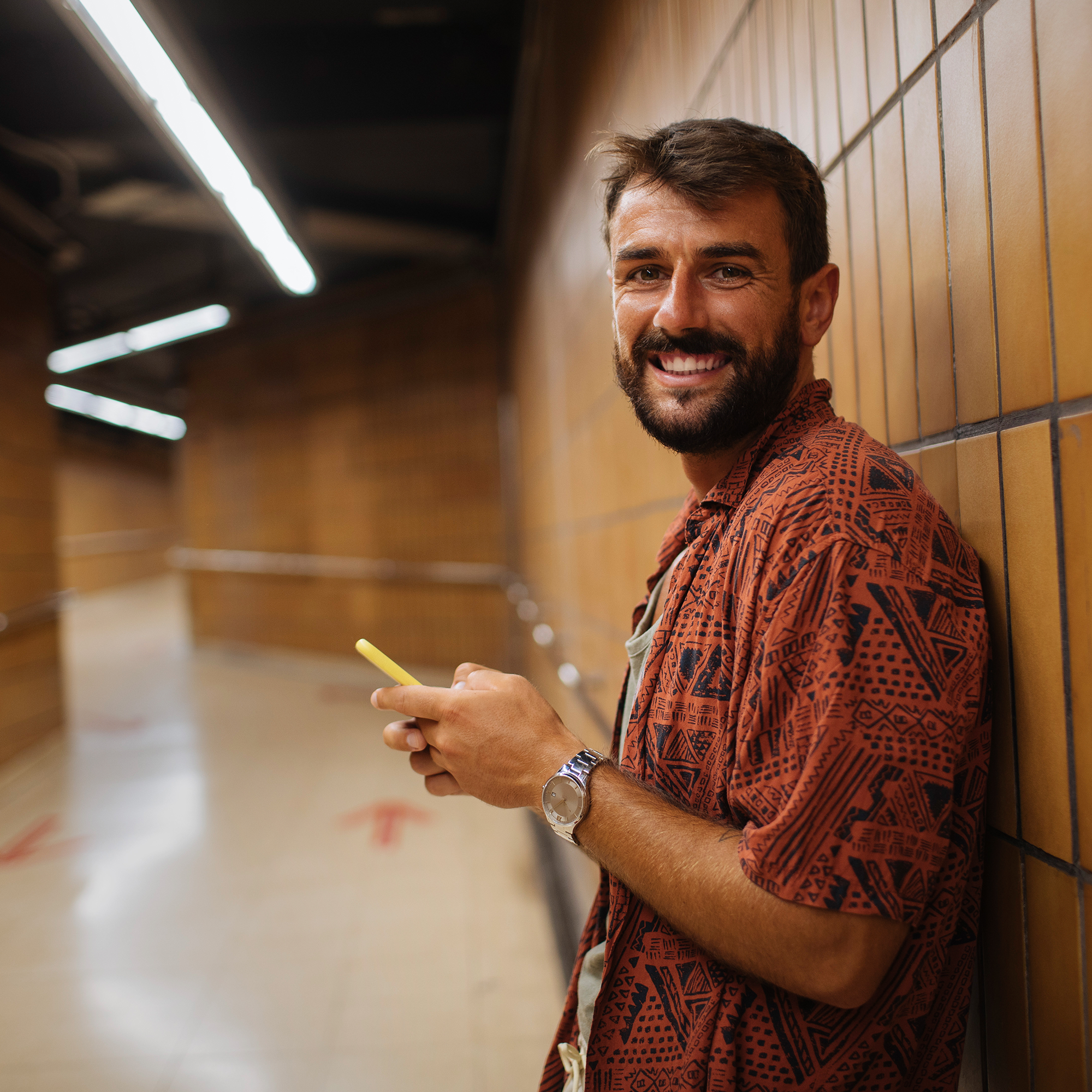 Smiling man using phone in underground corridor
