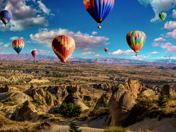 Colorful hot air balloons over rocky landscape and mountains