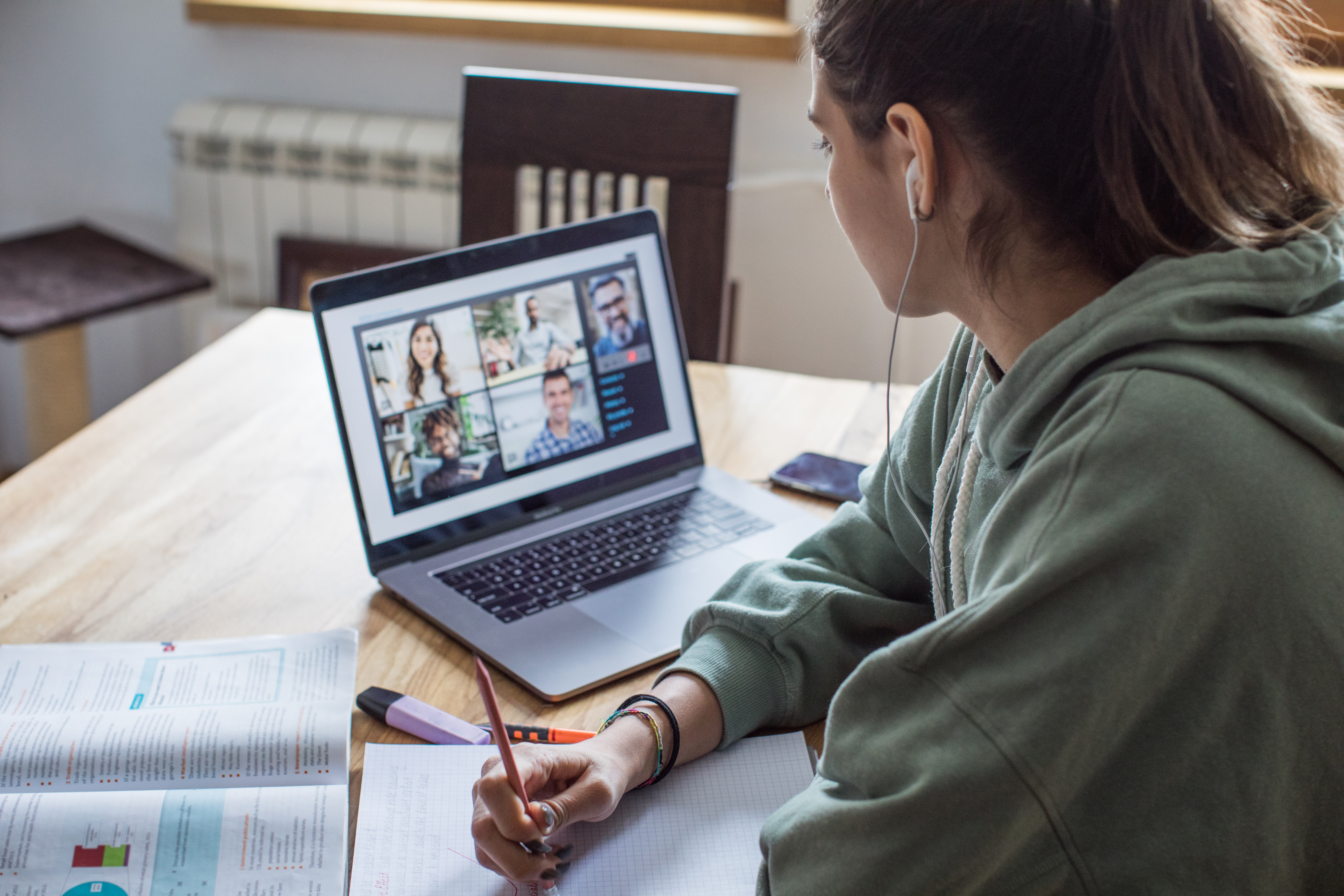 Person attending online meeting while taking notes