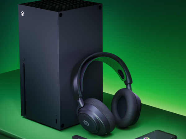Black Xbox console, headset, and smartphone on green surface