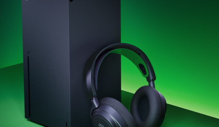 Black Xbox console, headset, and smartphone on green surface