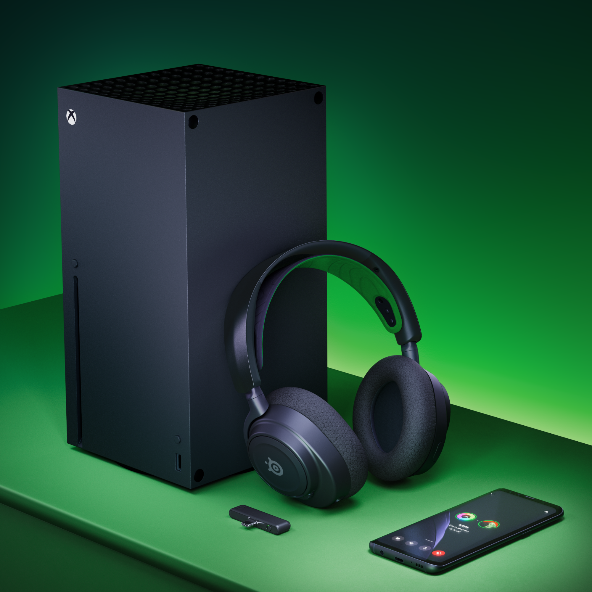 Black Xbox console, headset, and smartphone on green surface