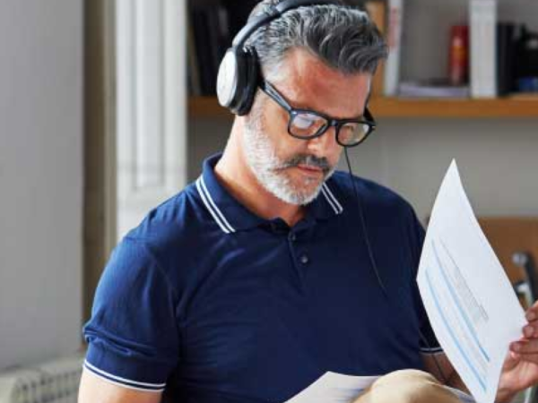 Man wearing headphones reviewing documents in office