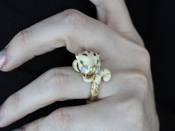 Hand wearing tiger-shaped gold ring with green eyes