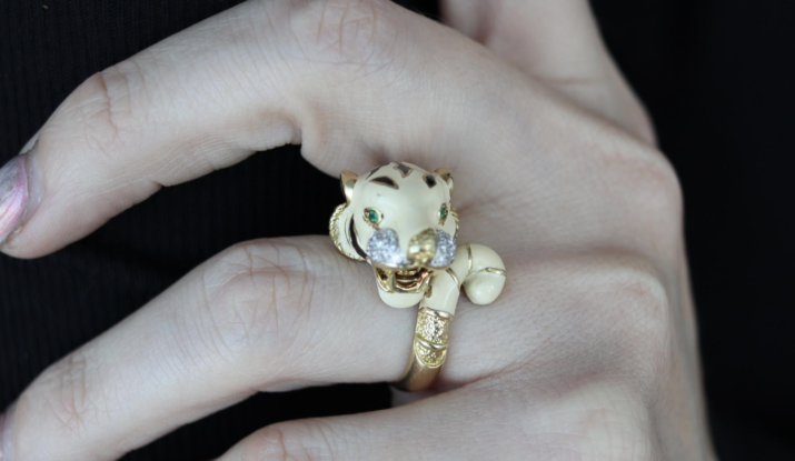 Hand wearing tiger-shaped gold ring with green eyes