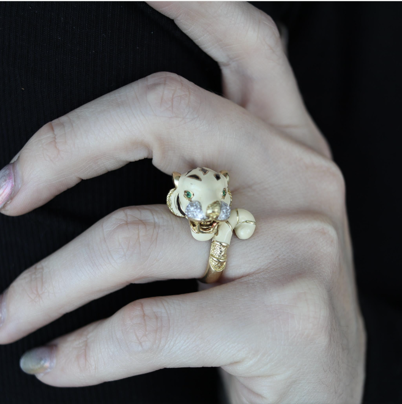 Hand wearing tiger-shaped gold ring with green eyes