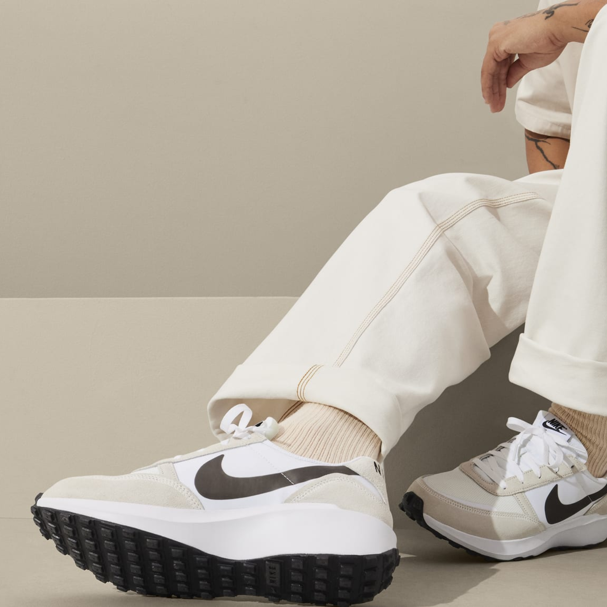 Person wearing white Nike sneakers and cream pants