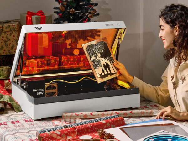 Woman holding laser-cut wood art near laser engraving machine