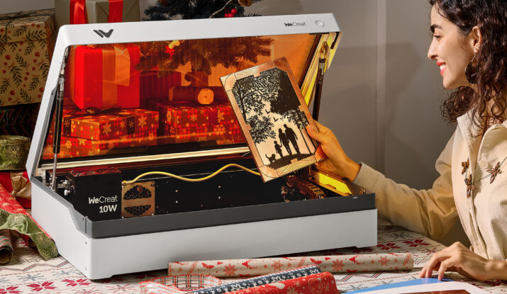 Woman holding laser-cut wood art near laser engraving machine