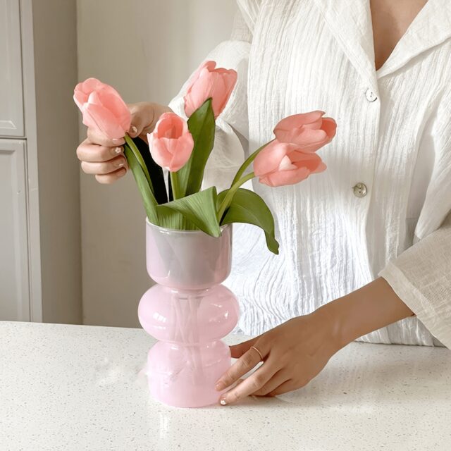 Person arranging pink tulips in pink vase