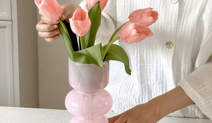 Person arranging pink tulips in pink vase