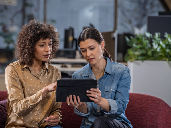 Two women looking at a tablet together indoors