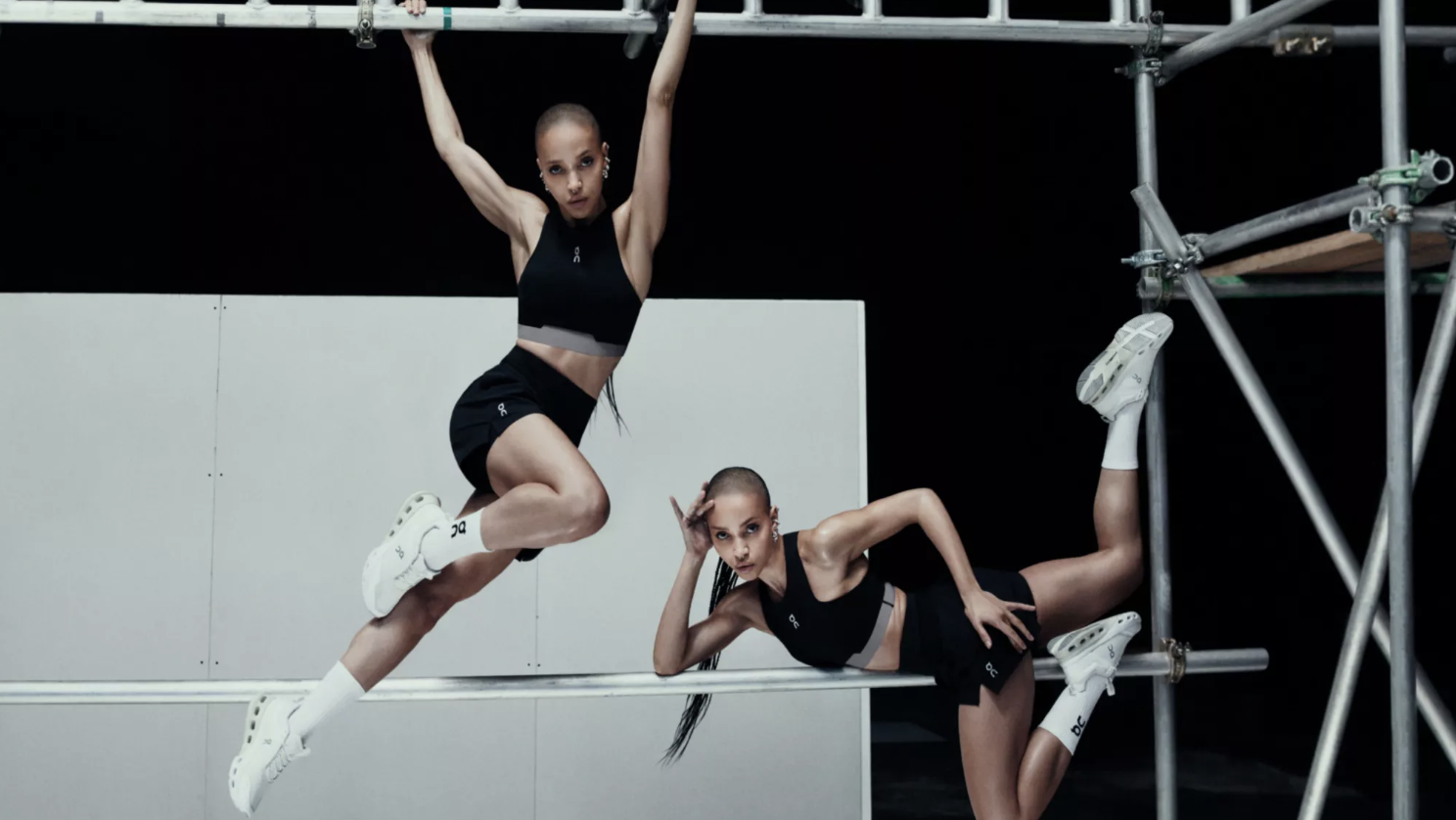 Two athletic women posing on metal scaffolding in black activewear