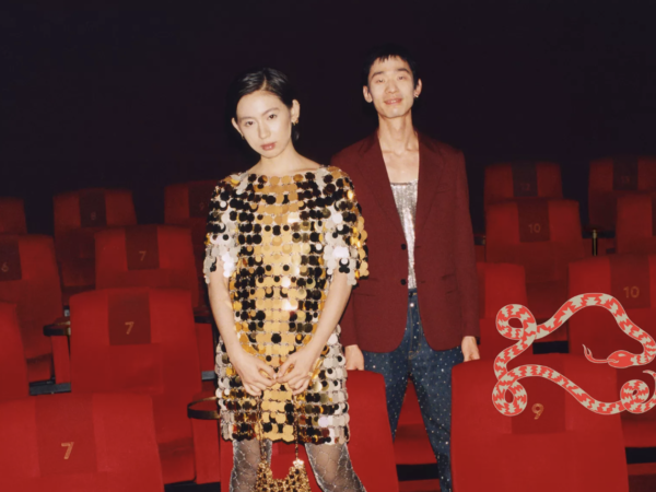 Two fashionably dressed people standing among red theater seats