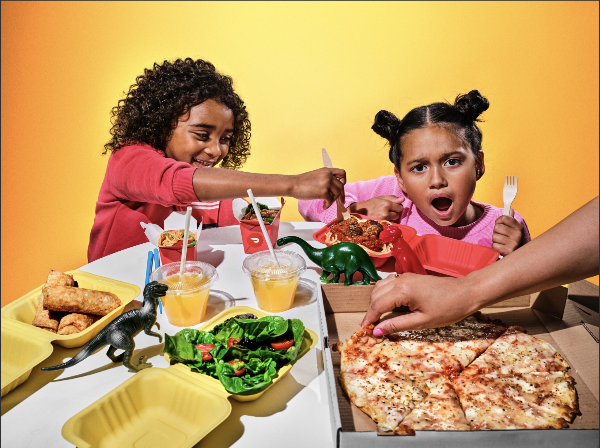 Children eating food with dinosaur toys on table