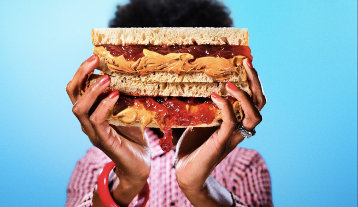 Person holding large peanut butter and jelly sandwich