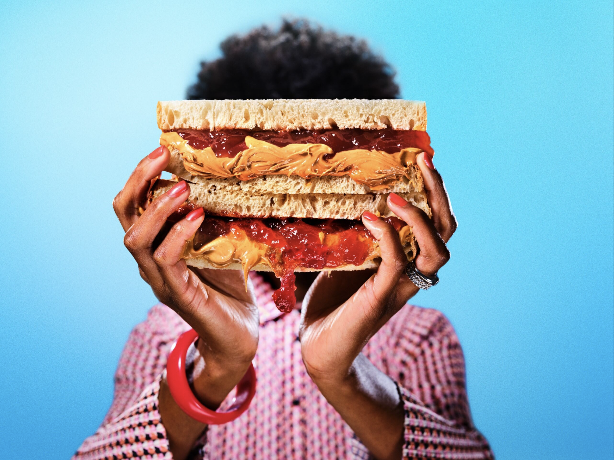 Person holding large peanut butter and jelly sandwich