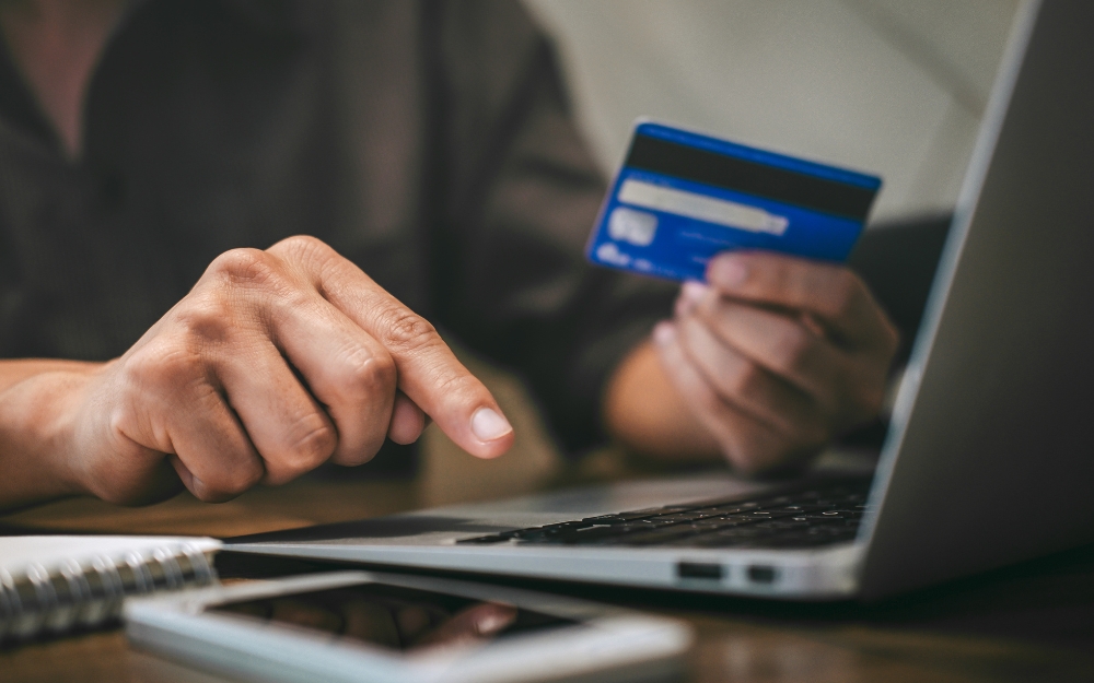 Person using laptop and holding credit card for payment