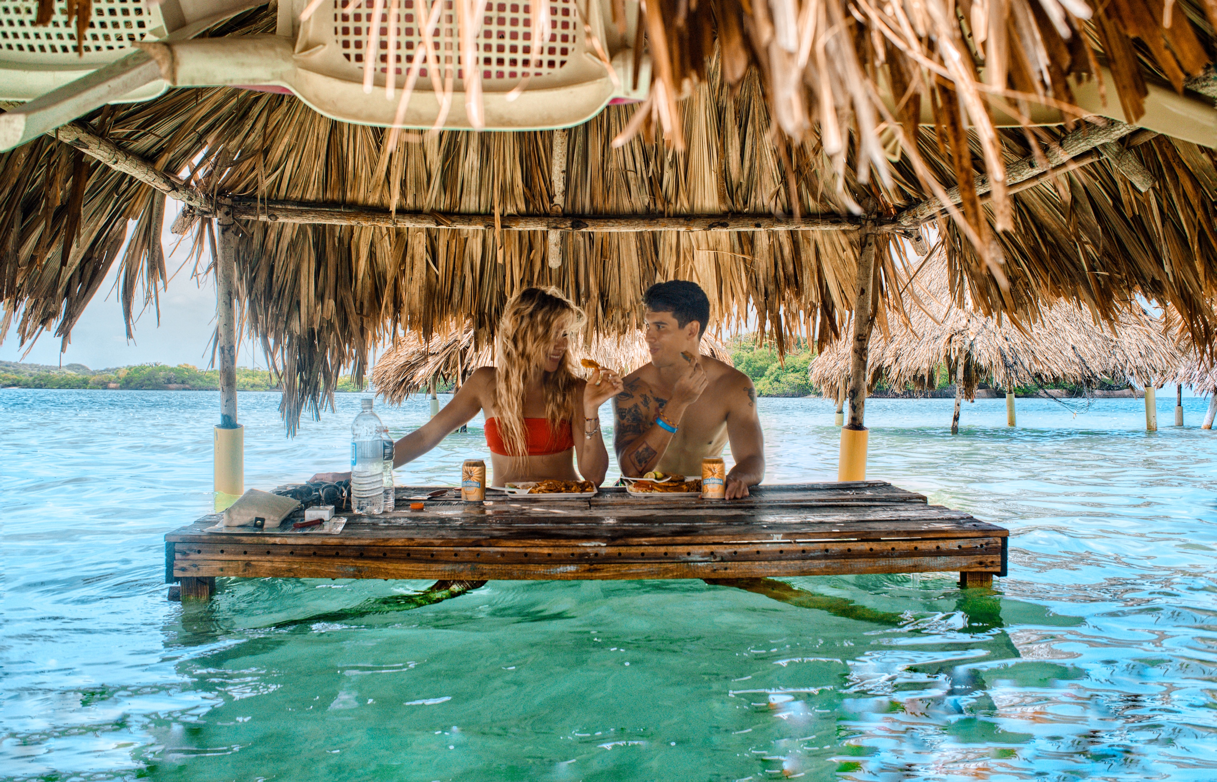 Couple eating under thatched hut in shallow water