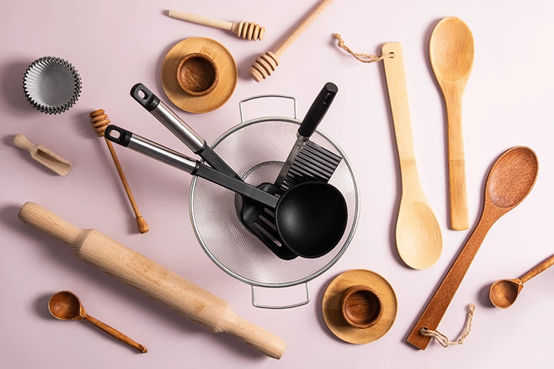 Various wooden and metal kitchen utensils arranged flat