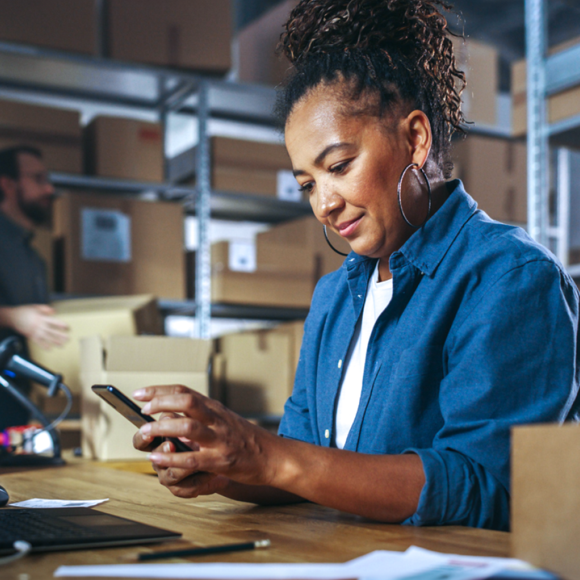 Woman using smartphone in busy warehouse setting
