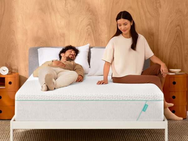 Man lying on bed, woman sitting beside peacefully