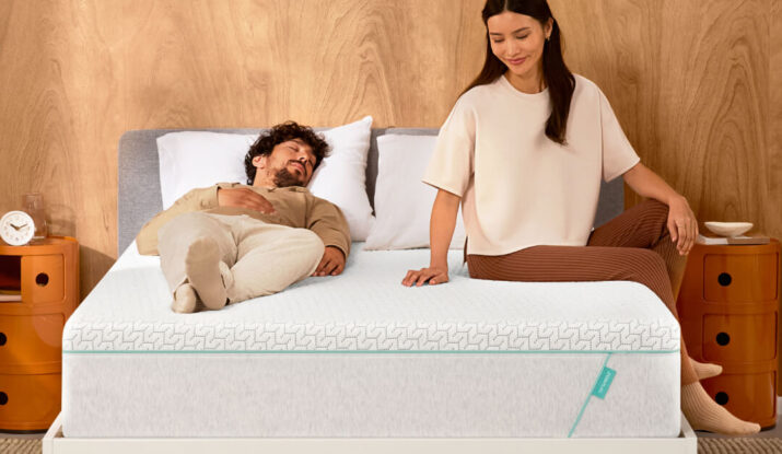 Man lying on bed, woman sitting beside peacefully