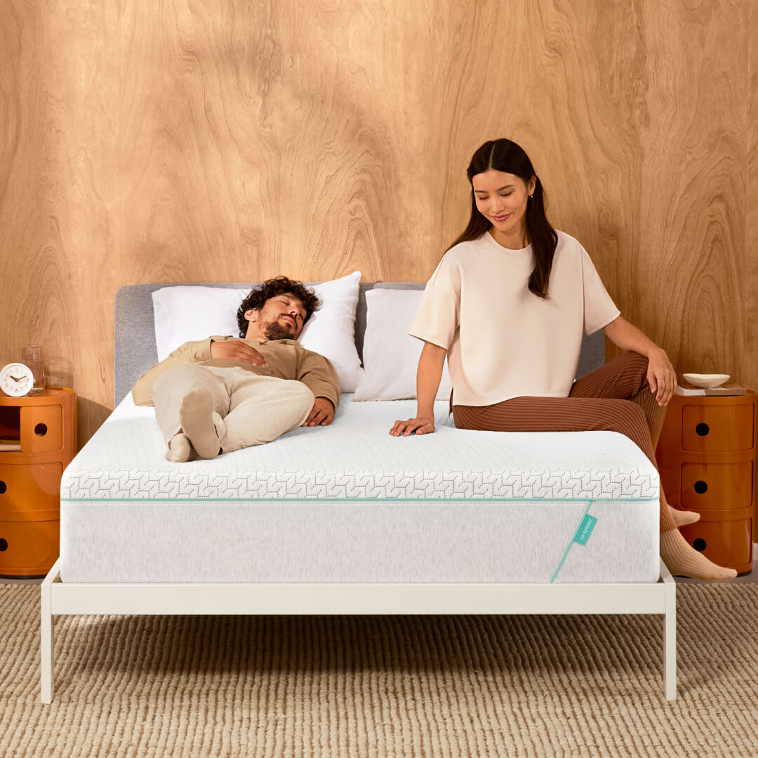 Man lying on bed, woman sitting beside peacefully