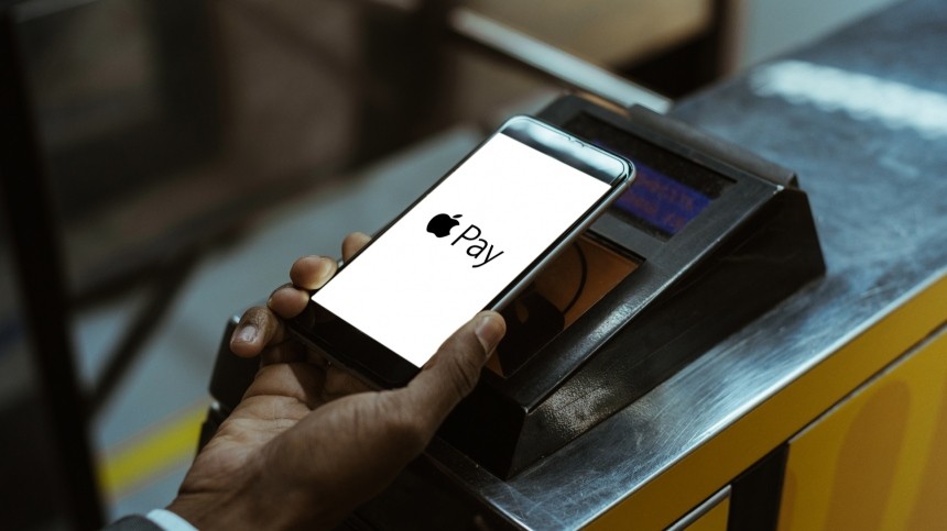 Hand holding phone with Apple Pay at payment terminal