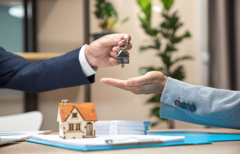 Handing over house key with miniature house on table