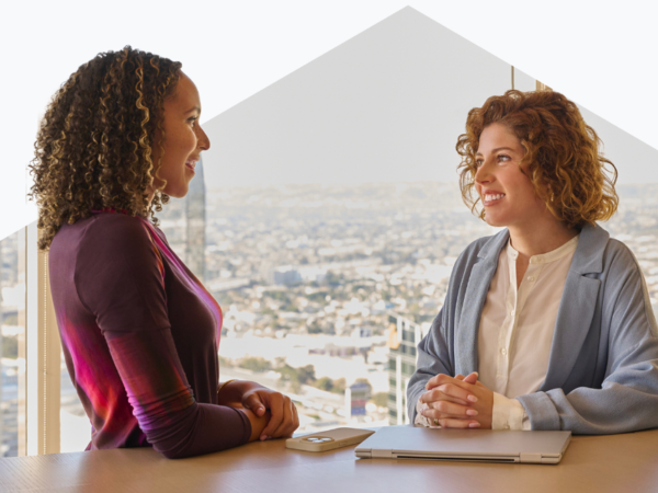 Two women smiling, conversing at a table
