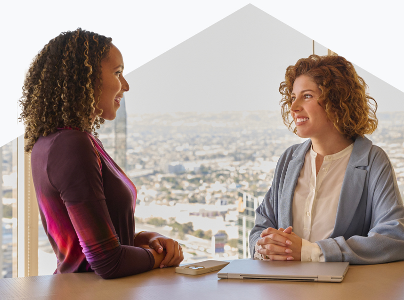 Two women smiling, conversing at a table