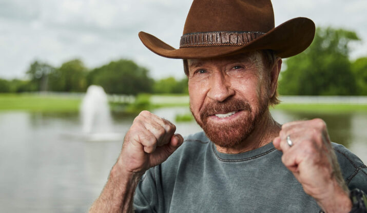 Smiling man wearing cowboy hat with fists raised