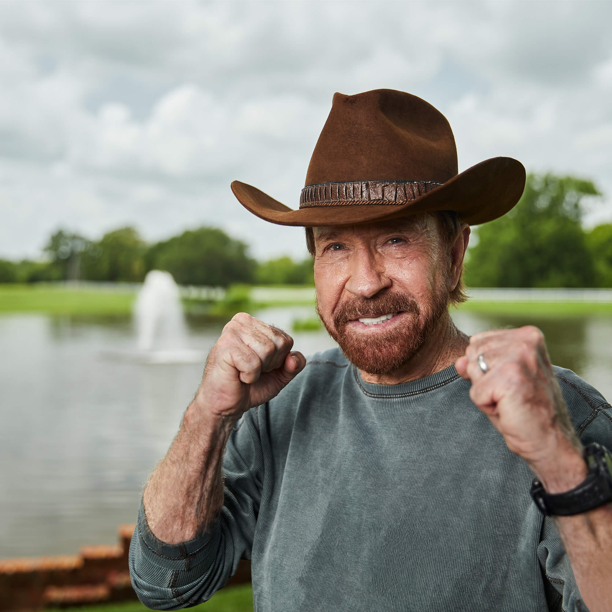 Smiling man wearing cowboy hat with fists raised