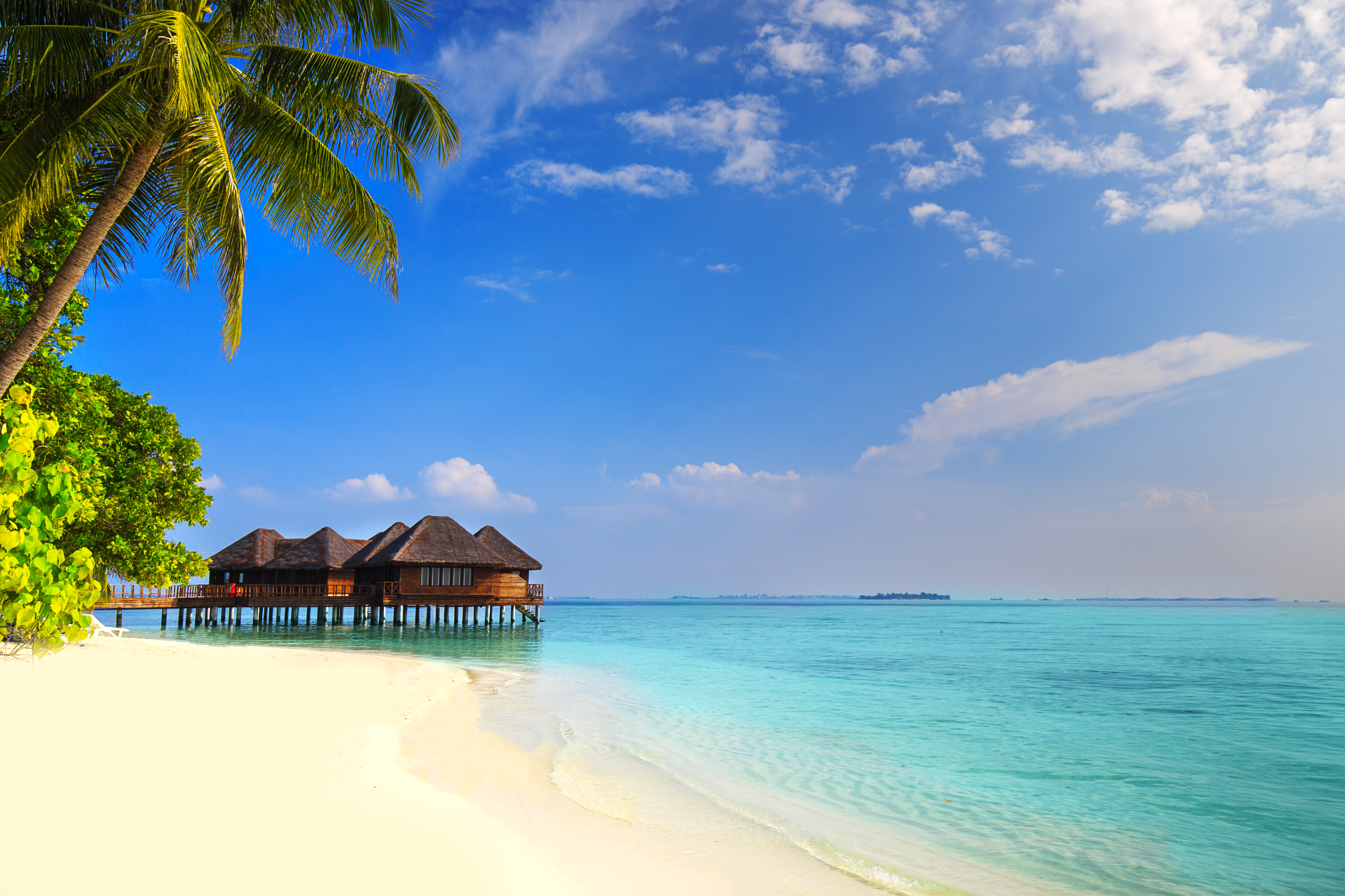 Thatched beach huts on stilts over turquoise water