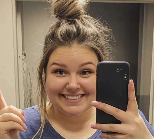 Smiling woman taking selfie with phone indoors