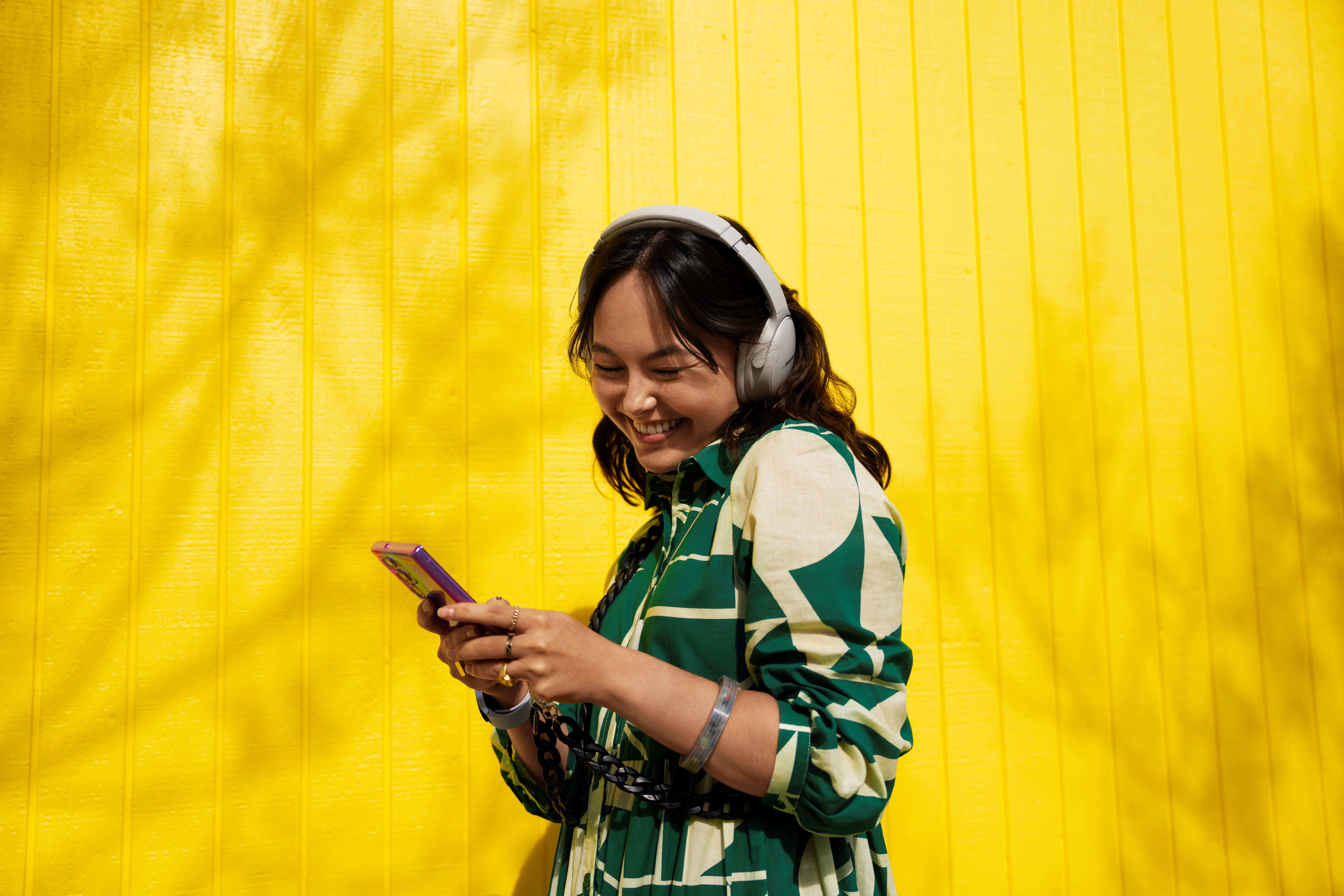 Woman smiling, wearing headphones, using phone
