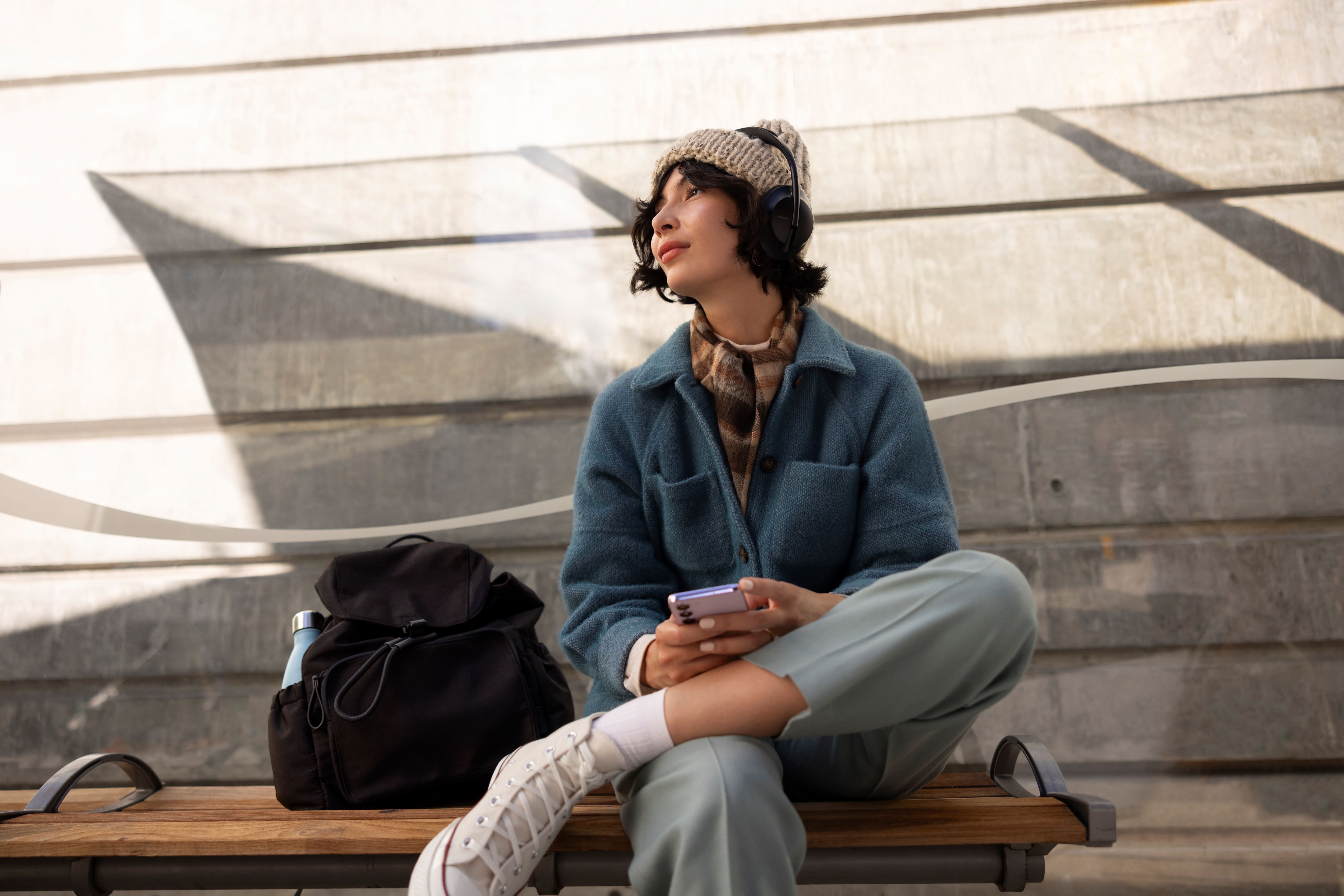 Young woman listening music outdoors, holding phone