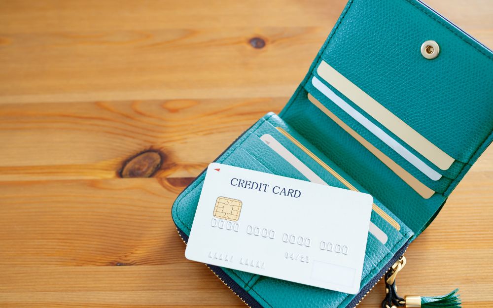 Credit card in open teal wallet on wooden table