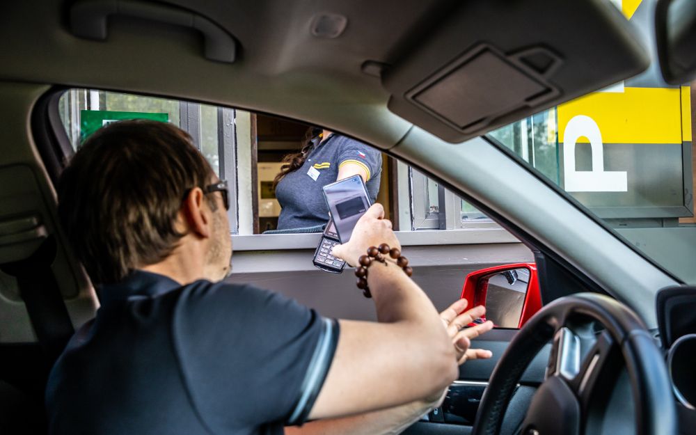 Man paying with phone at drive-thru window