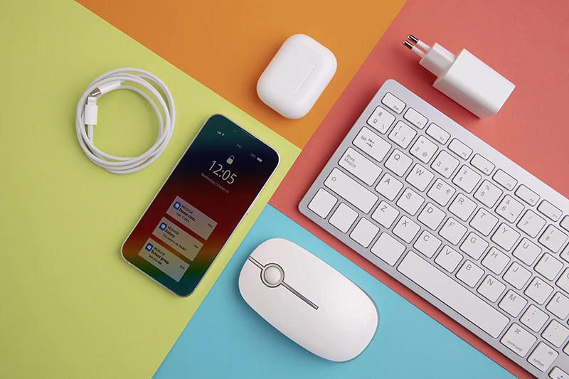 Smartphone, white mouse, keyboard, charger, and earbuds