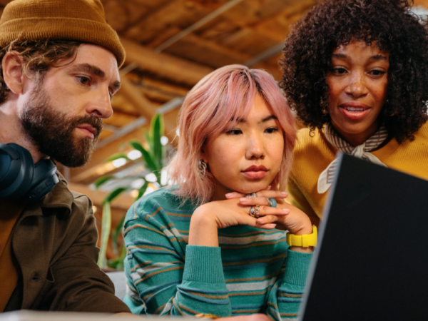 Three people focused on laptop screen together