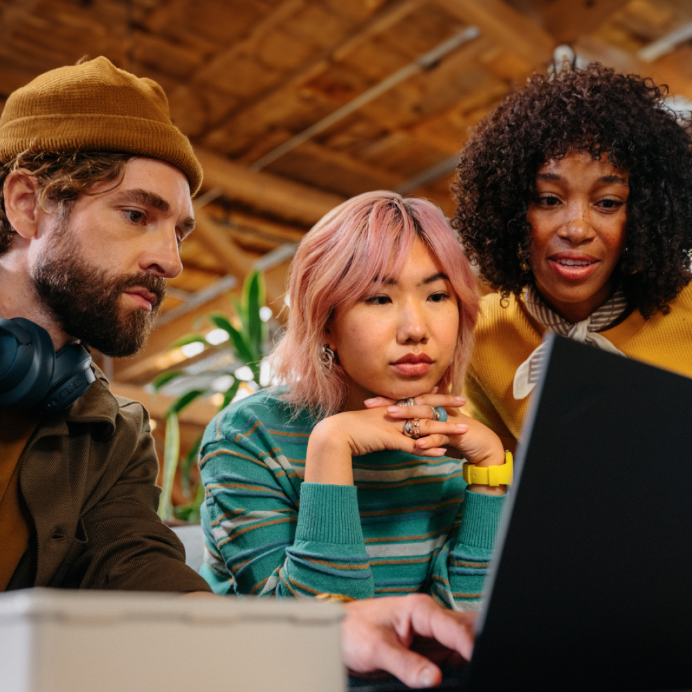 Three people focused on laptop screen together