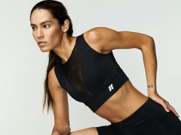 Fit woman in black workout wear leaning forward