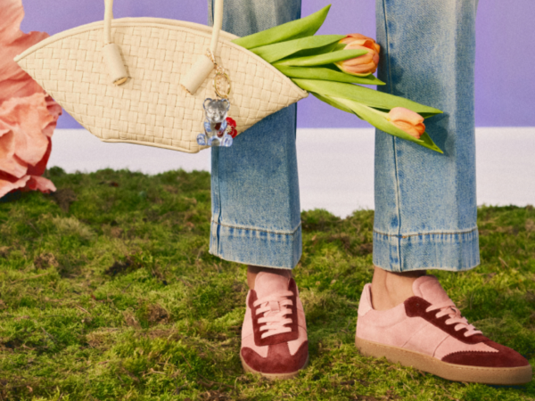 Person in jeans with pink shoes holding tulips and woven bag
